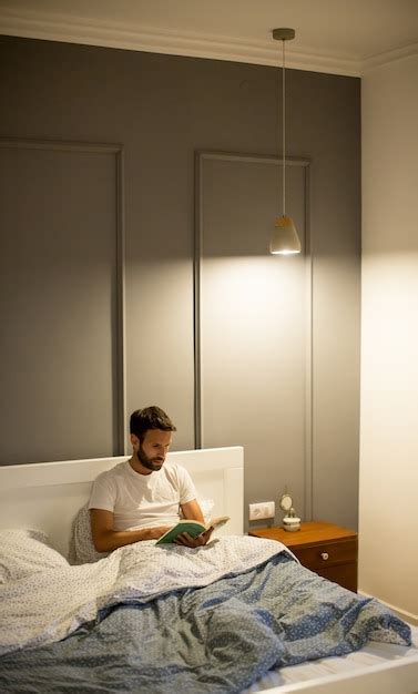 Premium Photo | Young man reading book in bed