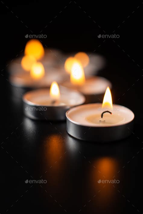 front view of burning candles on a pitch black surface funeral war ...