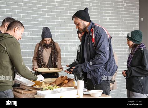 Volunteers giving food to homeless people in warming center Stock Photo - Alamy