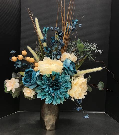 a vase filled with blue and yellow flowers on top of a black table next ...