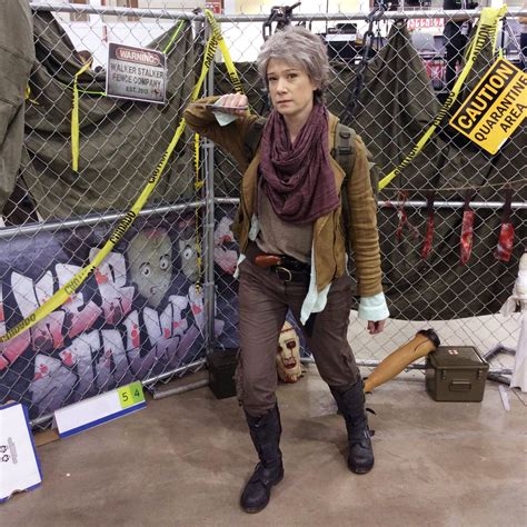 a woman standing in front of a fence holding a baseball bat and wearing ...