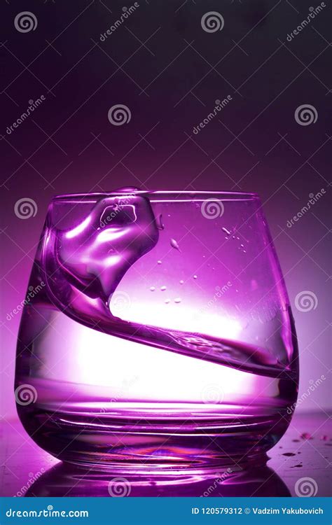 Splash the Liquid in a Glass. Photographed on a Colored Background. Backlight Control. Stock ...