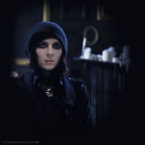 a woman with black hair wearing a hoodie and looking at the camera in a dark room