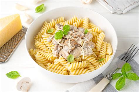 Fusilli Pasta with Mushrooms, Cheese and Fresh Basil in a Plate on a White Wooden Background ...