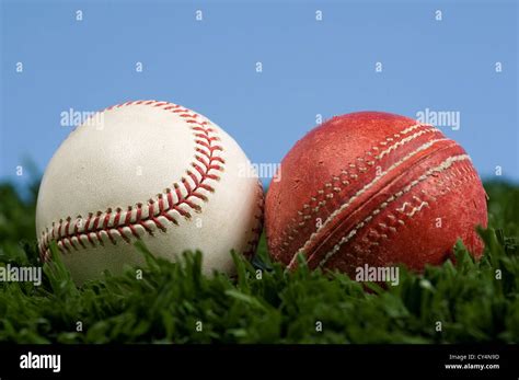 cricket ball and baseball on grass with blue sky - illustration of the way things change ...