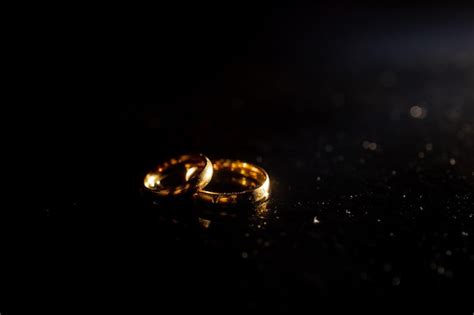 Premium Photo | Two golden wedding rings on black background