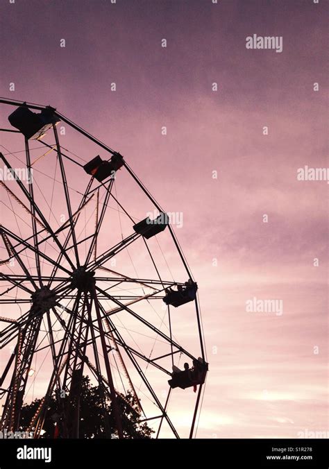 Silhouette of a Ferris wheel at sunset against a pink sky, UK Stock Photo - Alamy