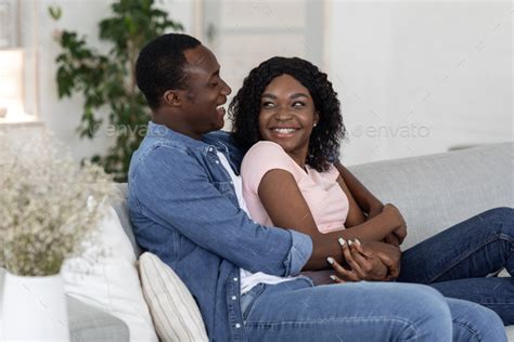 Happy young black man and woman hugging and having conversation Stock Photo by Prostock-studio