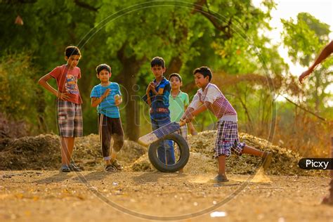 Image of Indian Rural Village Kids Playing Cricket In Fields-TA606336-Picxy