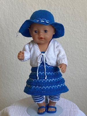 a small doll wearing a blue hat and dress on top of a white tablecloth