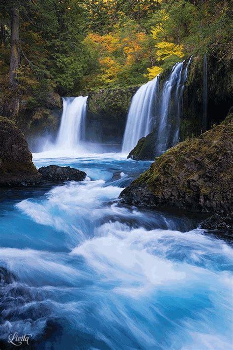 a waterfall in the woods with blue water