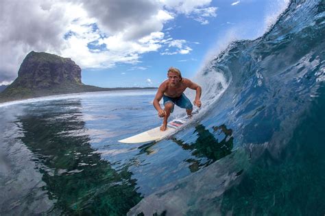 surfing in Mauritius - muscular surfer with long white hair riding on big waves on the Indian ...