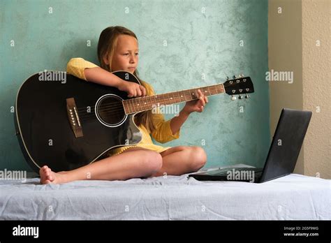 a little girl is learning to play the guitar Stock Photo - Alamy