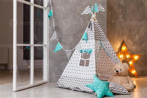 Stylish modern children room. Kid's wigwam in children room. Large wooden star lamp. Interior ...