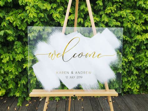 a welcome sign on an easel with greenery in the background