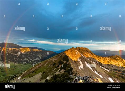 Full rainbow around a mountain peak st sunrise Stock Photo - Alamy