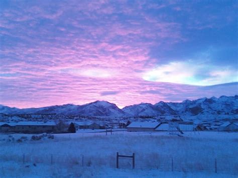 the sky is pink and purple as it sits in front of some snow covered ...