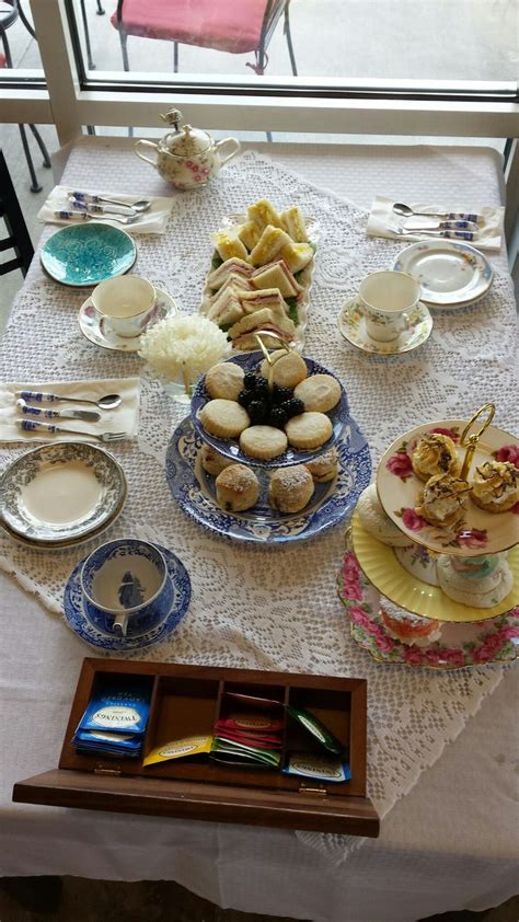 Traditional afternoon tea set up with mini scones, shortbread, sandwiches, and assorted desserts ...