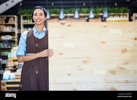 Shop assistant in uniform standing by wooden billboard Stock Photo - Alamy