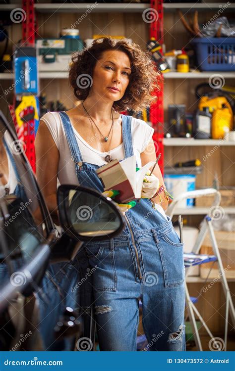 Adorable Woman Car Mechanic in Blue Overalls with a Book-instruction ...