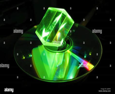 Glass prism and laser. Glass prism illuminated with green laser light, with a reflection seen in ...