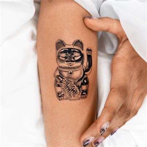 Maneki-neko tattoo located on the forearm.