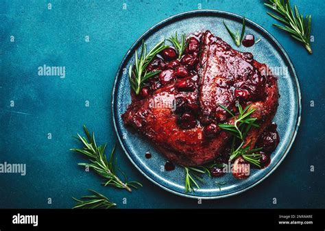 Baked duck legs in cherry and red wine sauce with rosemary. Delicacy dinner. Blue table ...