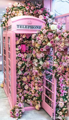 a pink phone booth covered with flowers and greenery in a mall or shopping center