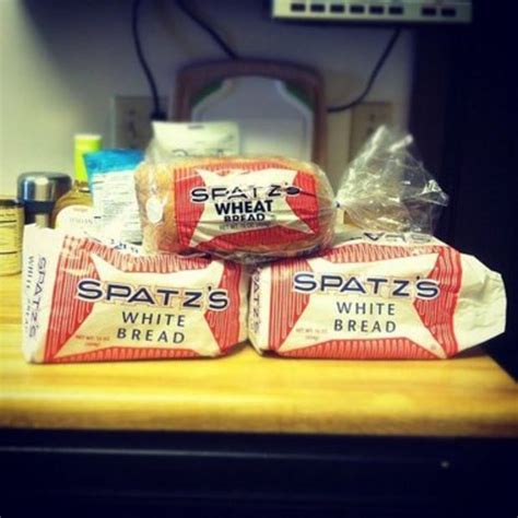 three bags of spatz's white bread sitting on top of a wooden table