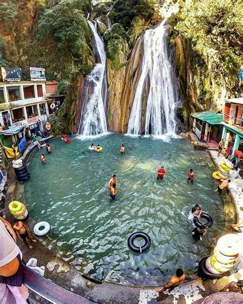 people are swimming in the water near a waterfall