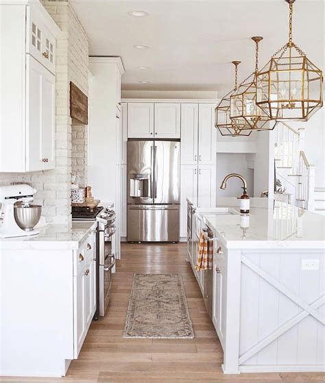 white kitchen, large gold light fixtures in kitchen, painted brick in ...