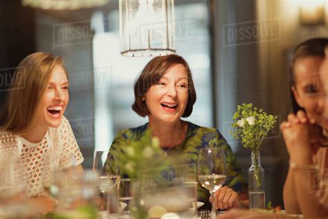 Laughing women friends dining and talking at restaurant table - Stock ...