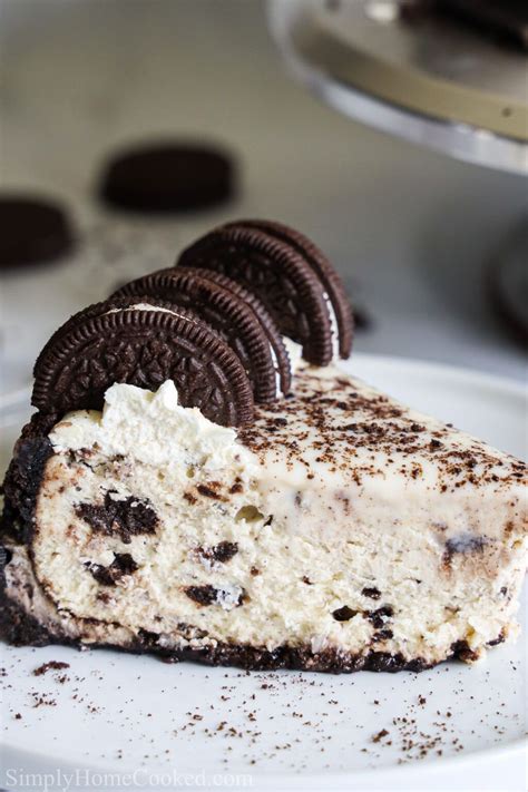 close up side view of a slice of Easy Oreo Cheesecake with Oreos on top, on a white plate ...