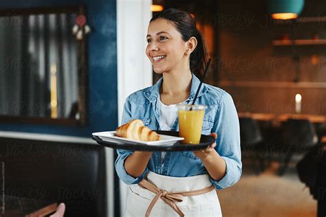 Smiling Waitress Carrying An Order Of Food In A Cafe by Flamingo Images