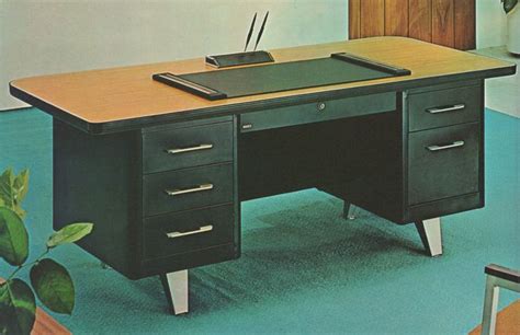 an office desk with two drawers and a pen holder on the top, in front of a plant
