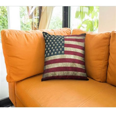 an american flag pillow sitting on top of a yellow couch next to a large window