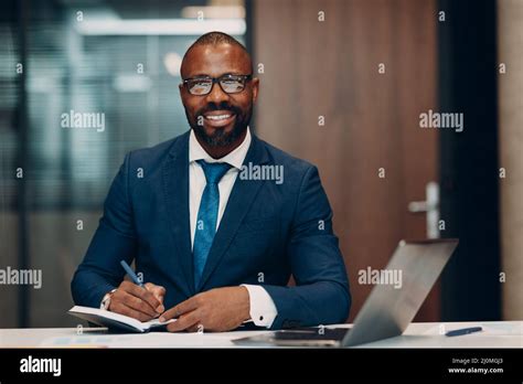 Portrait smiling african american businessman in blue suit sit at table ...