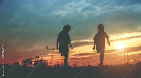 Silhouette, group of happy children playing on meadow, sunset ...