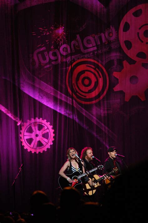 two women on stage playing instruments in front of a purple background ...