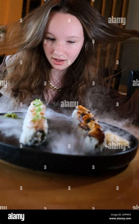 satisfied girl teenager laughing smiling against background of large plate with set of sushi ...