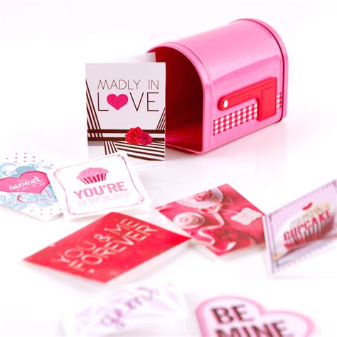 a pink mailbox sitting on top of a white table next to some stickers
