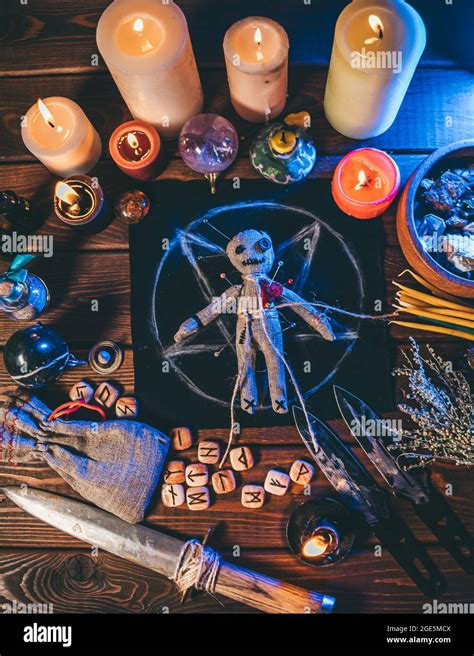 Voodoo doll on wooden table with candles and occult objects, top view. Magic and dark spooky ...