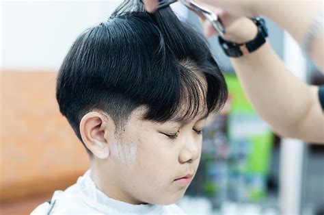 Asian boy is cut his hair in barber shop - people in hairdresser beauty ...