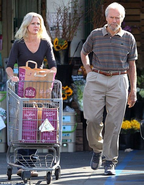 an older man and woman walking down the street with shopping carts full ...