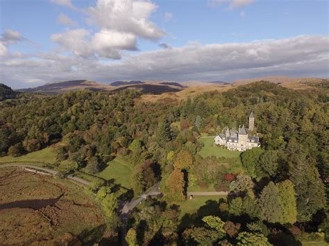 an aerial view of a castle in the middle of a green field with trees and hills