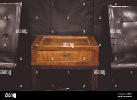 Small wooden table between two leather chairs Stock Photo - Alamy