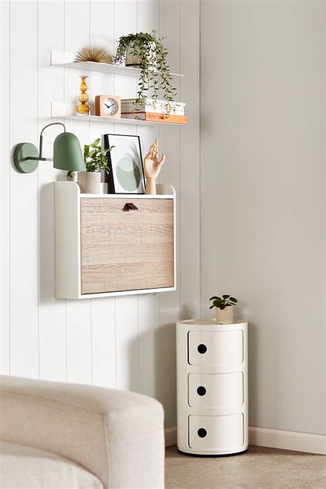 a living room with white walls and shelves filled with potted plants on ...