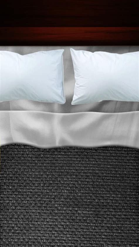 a bed with two white pillows and black carpet