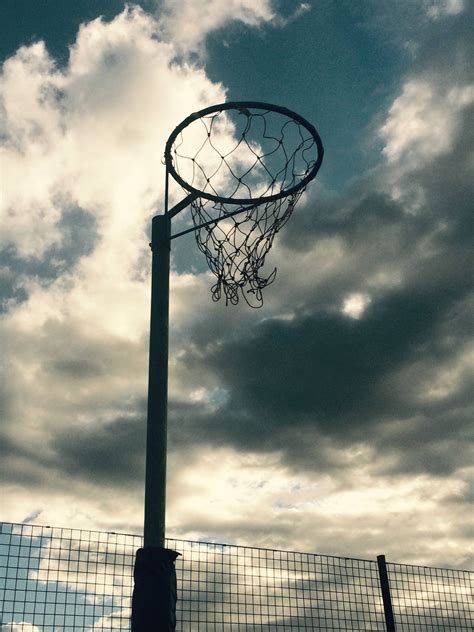 Download Victory at Her Fingertips – A Netball Player Aiming for the Hoop on an Outdoor Court ...