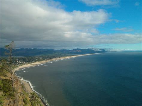 an aerial view of the beach and ocean with clouds in the blue sky above it